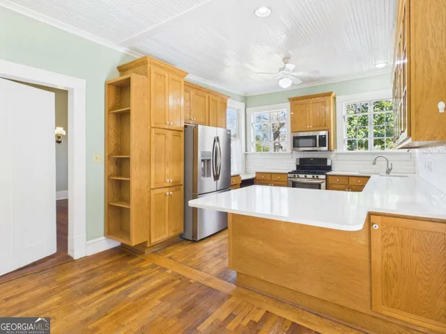 a kitchen with stainless steel appliances granite countertop a refrigerator a stove and a sink with couches