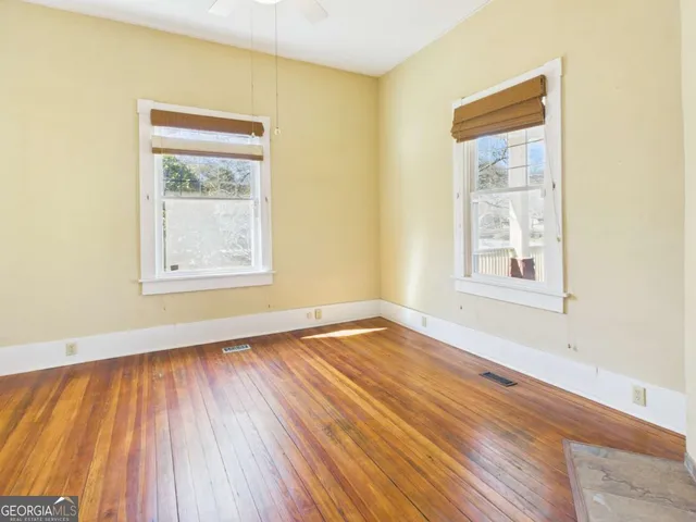a view of an empty room with wooden floor and a window