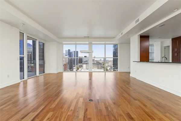 a view of empty room with wooden floor and furniture