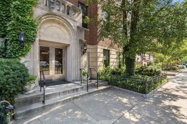 a view of a brick house with plants and large tree