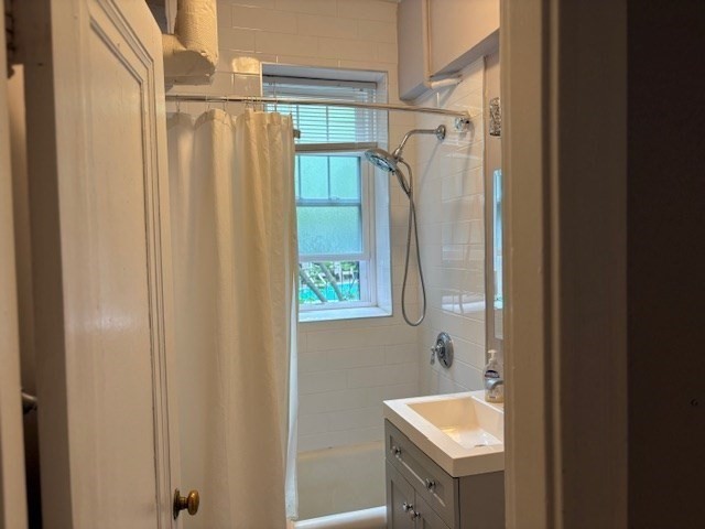 1945 Commonwealth Avenue, Unit 4 Boston, MA 02135 - Photo 12 of 22 a bathroom with a sink a mirror a bathtub and shower