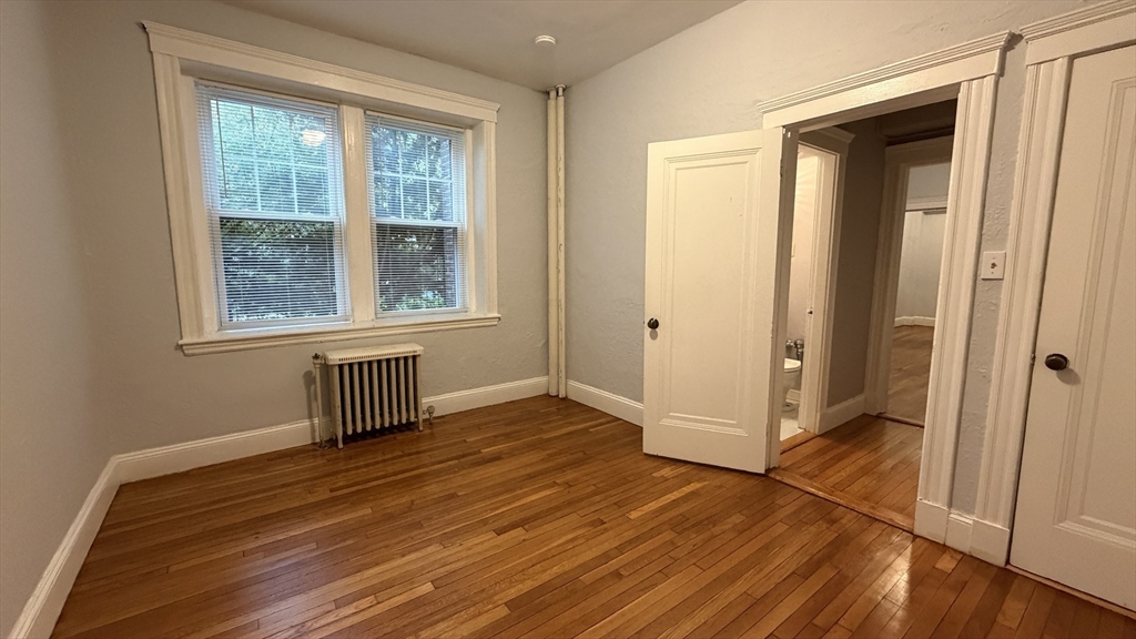 1945 Commonwealth Avenue, Unit 4 Boston, MA 02135 - Photo 16 of 22 an empty room with wooden floor and windows