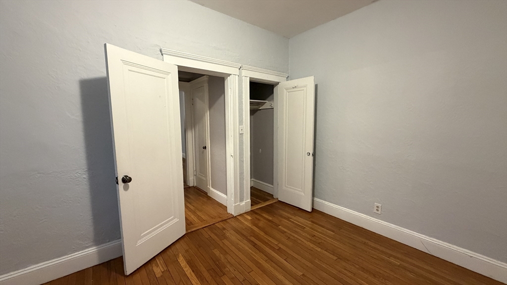 1945 Commonwealth Avenue, Unit 4 Boston, MA 02135 - Photo 17 of 22 a view of an empty room with wooden floor and a window