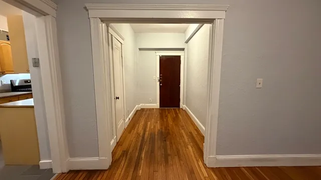 a view of a hallway with wooden floor and a bathroom