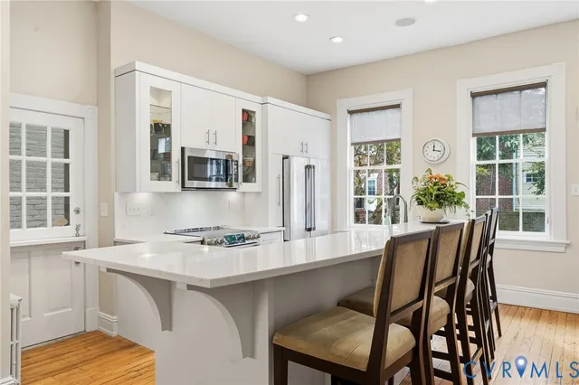 a large white kitchen with wooden floor and stainless steel appliances
