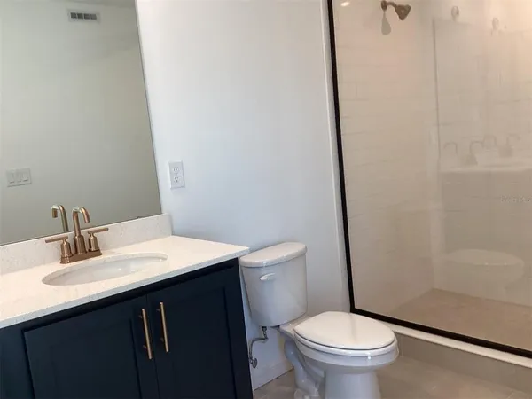a bathroom with a sink a toilet a mirror and shower