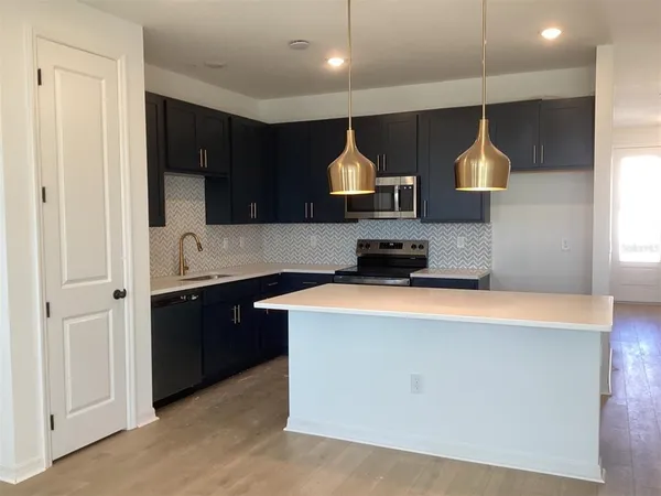 a kitchen with stainless steel appliances a sink a stove a refrigerator and a cabinets