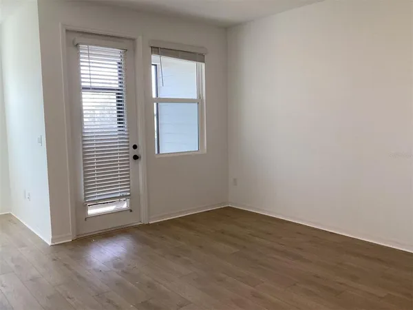an empty room with wooden floor and windows