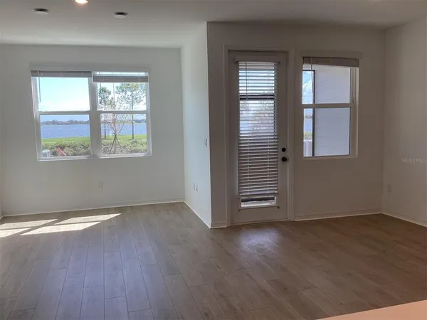 an empty room with wooden floor and windows