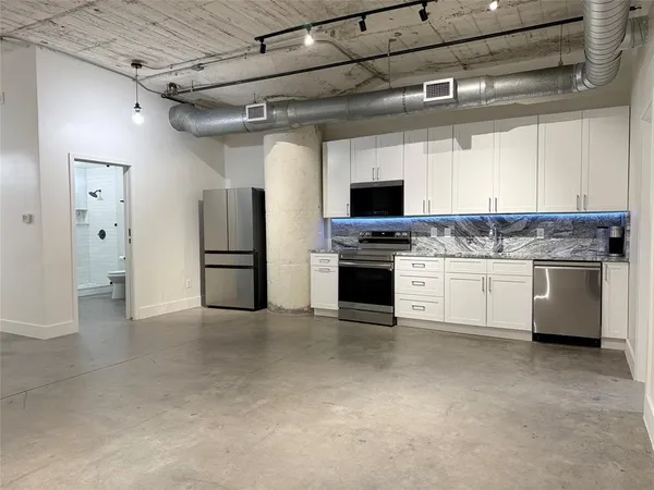 a kitchen with stainless steel appliances granite countertop a refrigerator and a stove top oven
