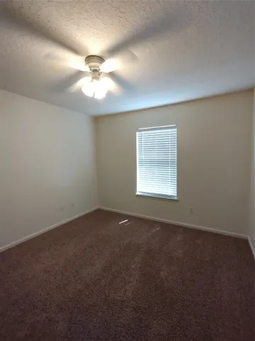 an empty room with a window and a fan