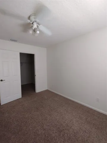 a view of an empty room with a chandelier fan