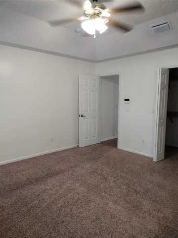 a view of an empty room with a chandelier fan