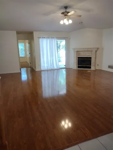 an empty room with wooden floor fireplace and windows