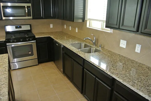 a kitchen with granite countertop a sink a stove and microwave