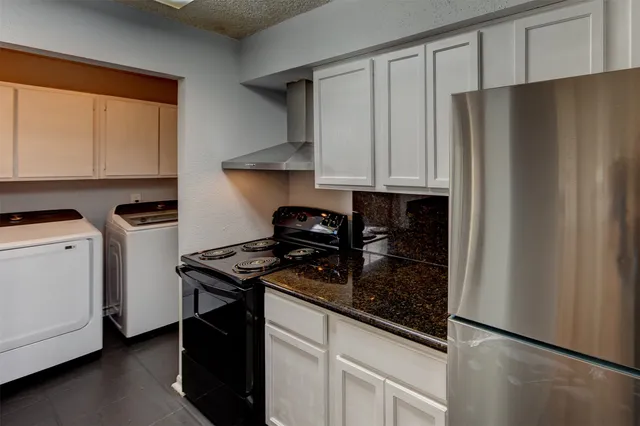 a kitchen with stainless steel appliances granite countertop a refrigerator a stove and a sink