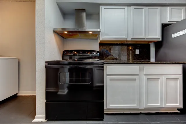 a kitchen with granite countertop white cabinets and stainless steel appliances