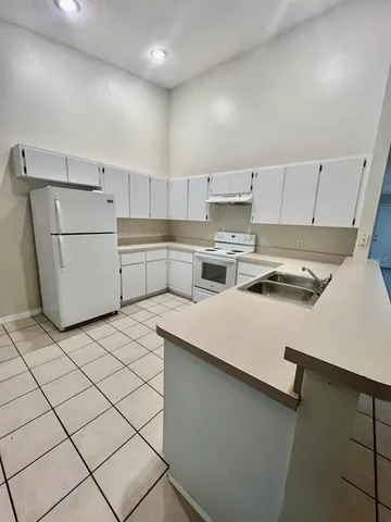 a kitchen with a refrigerator a stove top oven a sink and cabinets