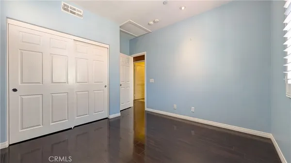 an empty room with wooden floor and closet area