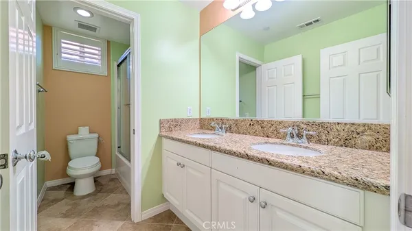 a bathroom with a granite countertop sink a toilet and a mirror