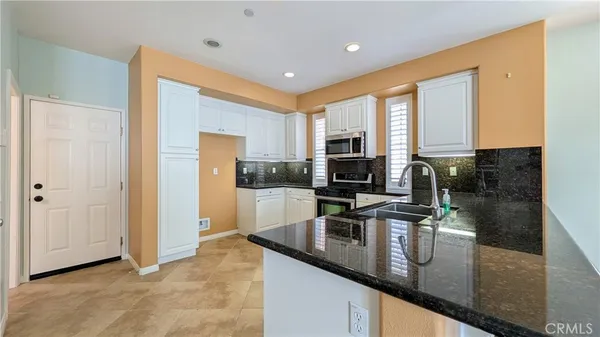 a kitchen with stainless steel appliances granite countertop a sink a stove and a refrigerator