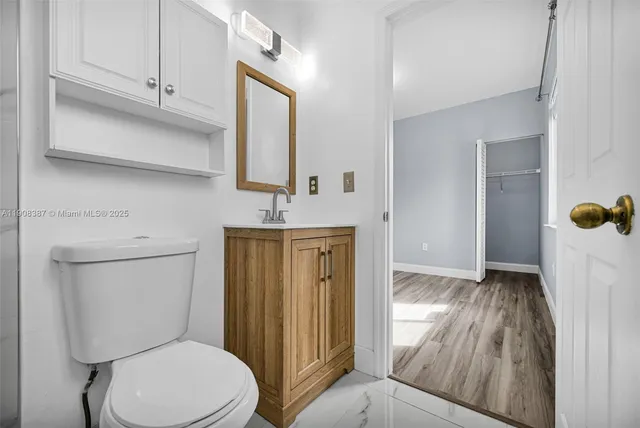 a view of an empty room with wooden floor and a ceiling fan