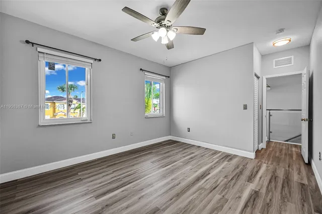 a view of a hallway with wooden floor and a livingroom with windows
