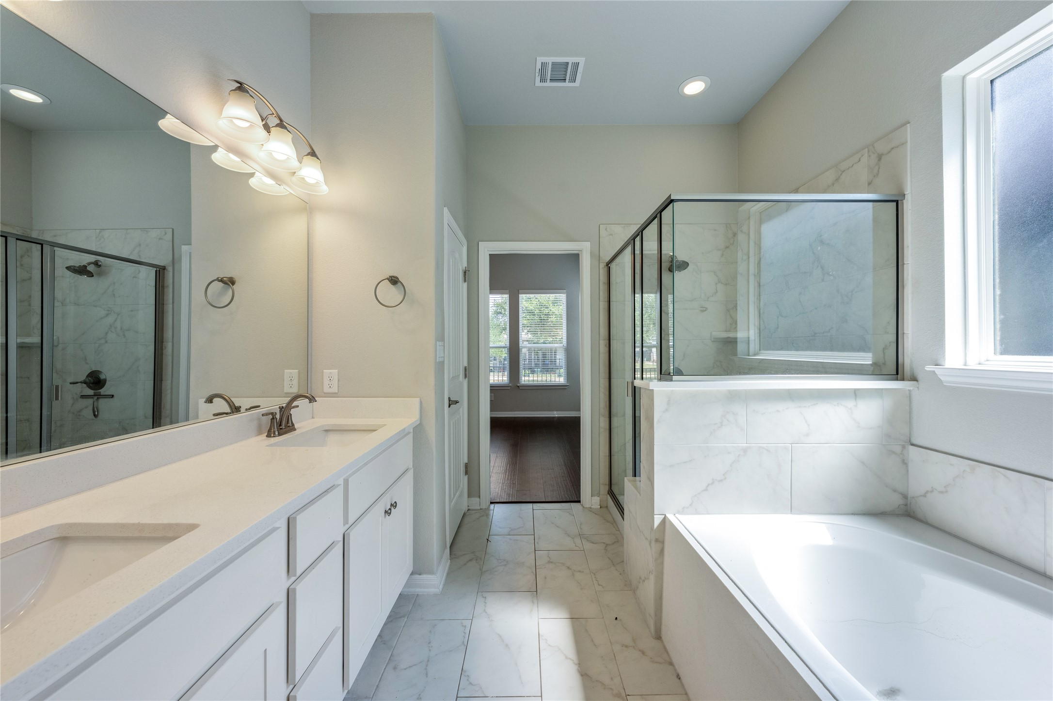 126 Rains Kyle, TX 78640 - Photo 13 of 22 A spacious bathroom displays dual vanities, high ceilings, a soaking tub, and a separate glass-enclosed shower.