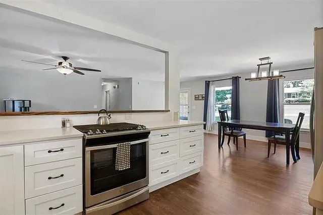 a kitchen with stainless steel appliances granite countertop a stove a sink dishwasher and a refrigerator with wooden floor