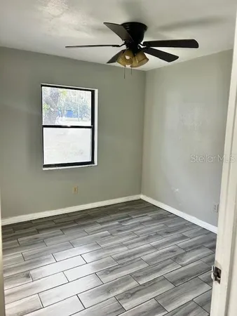 a view of an empty room with a window and a ceiling fan