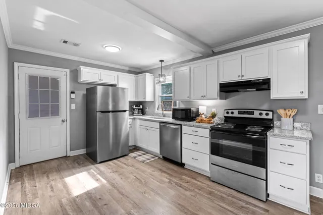 a kitchen with a refrigerator stove and white cabinets