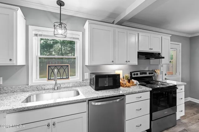a kitchen with granite countertop a sink stove and cabinets