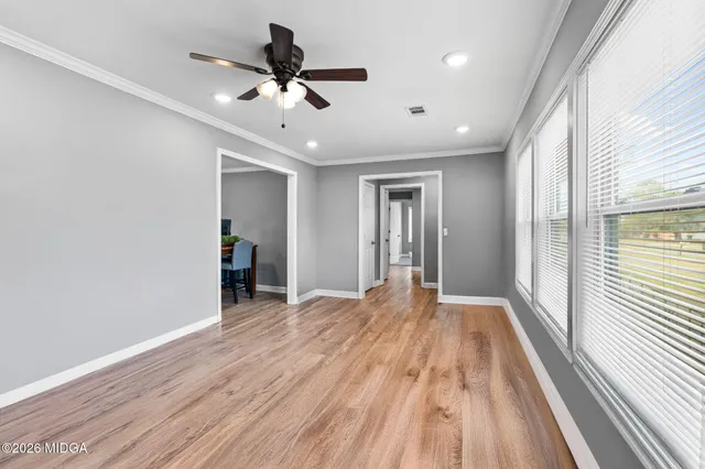 a view of an empty room with wooden floor and a window