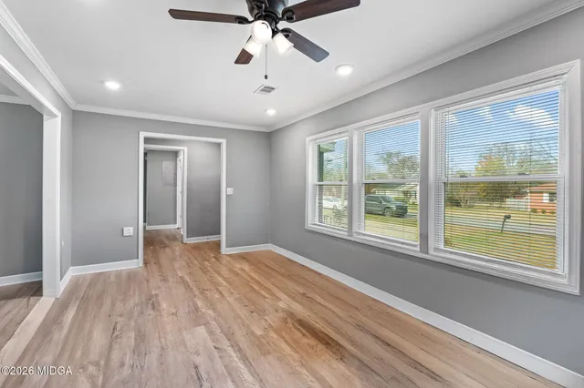 a view of an empty room with a window and wooden floor