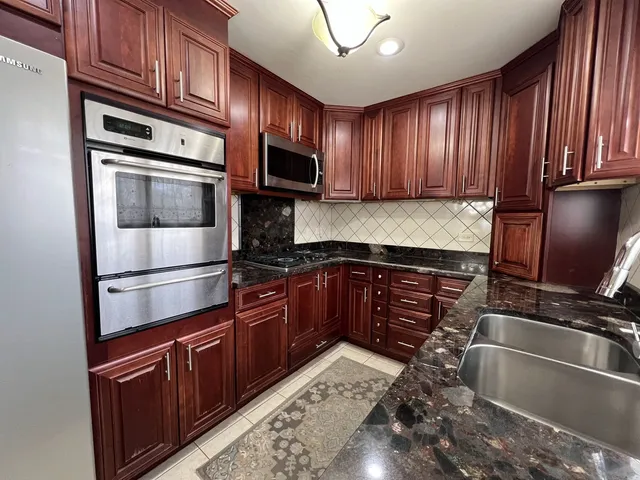 a kitchen with granite countertop wooden cabinets stainless steel appliances and a window