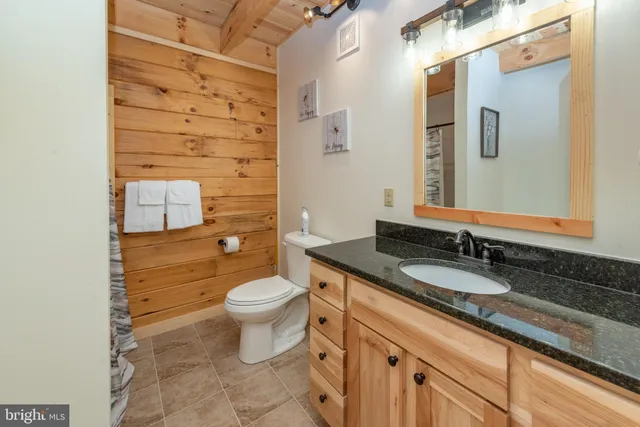 a bathroom with a granite countertop toilet sink and mirror