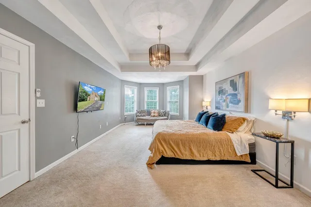 a spacious bedroom with a large bed and a chandelier