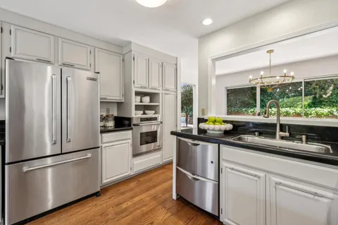 a kitchen with stainless steel appliances a refrigerator a stove a sink and white cabinets with wooden floor