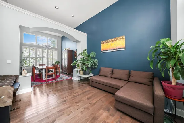 a living room with furniture potted plant kitchen view and a window