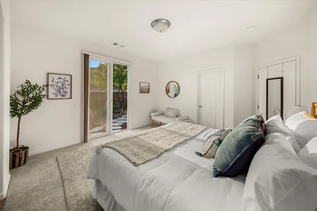 a bedroom with a bed and a potted plant next to a window