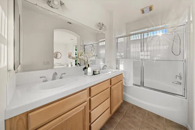 a bathroom with a double vanity sink mirror and shower