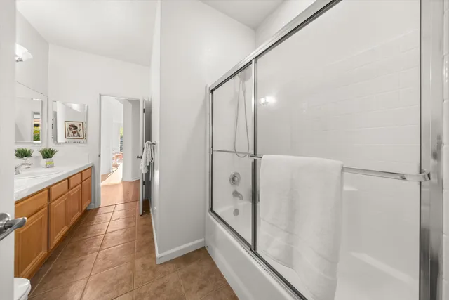 a large white bathroom with a glass shower door and a sink