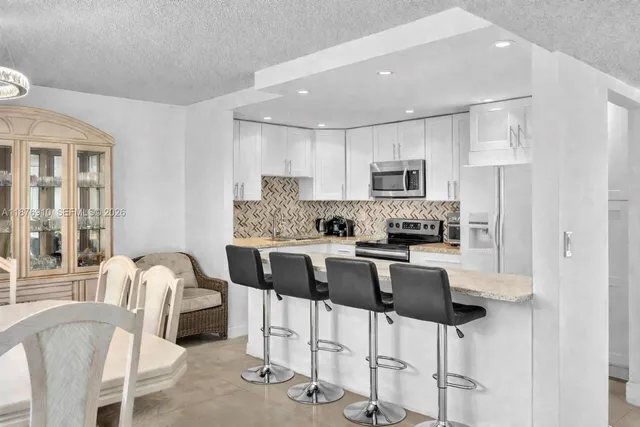 a kitchen with stainless steel appliances granite countertop a stove a refrigerator a microwave a dining table and chairs