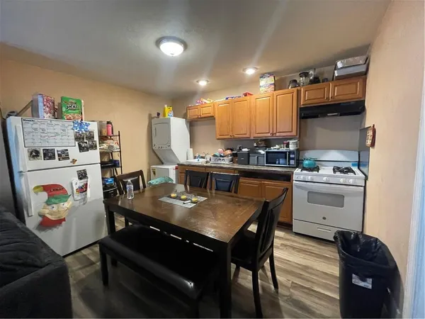 a kitchen with stainless steel appliances granite countertop a stove a refrigerator a sink a dining table and chairs with wooden floor