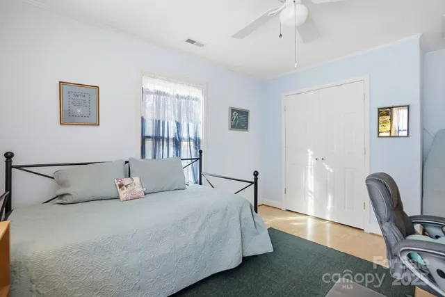 a bedroom with a bed wooden floor and a chair