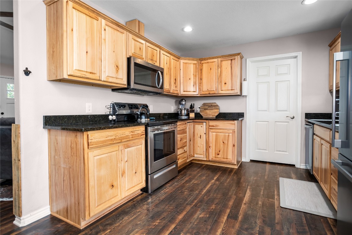 295 Garden City Road Livingston, TX 77351 - Photo 7 of 20 a kitchen with stainless steel appliances granite countertop white cabinets a sink a stove a refrigerator and microwave with wooden floor