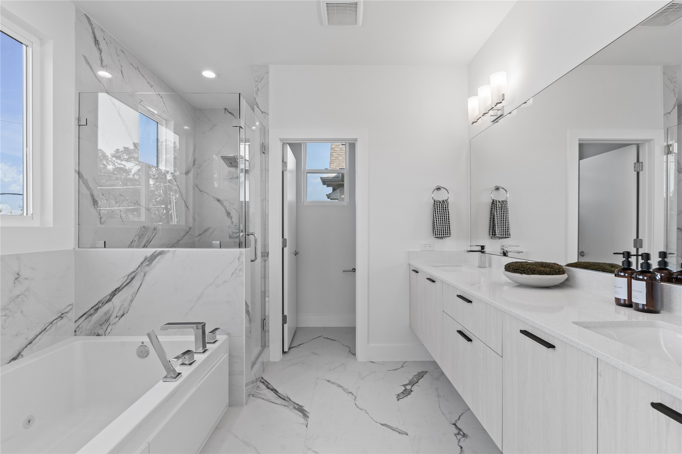 1810 Yates Street Houston, TX 77020 - Photo 19 of 30 Spa-like primary bath featuring a floating double vanity, soaking tub & frameless glass shower all wrapped in elegant marble-inspired tile for a clean, modern finish.
