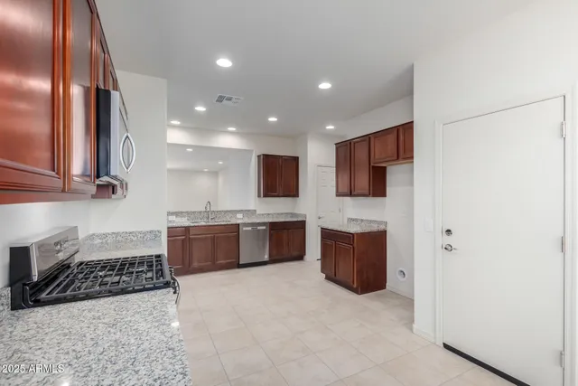 a large white kitchen with stainless steel appliances granite countertop a stove a sink and a refrigerator