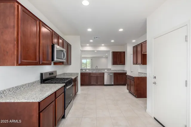 a large kitchen with stainless steel appliances granite countertop a refrigerator and a stove top oven