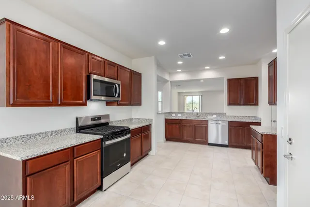 a kitchen with stainless steel appliances granite countertop wooden cabinets a stove top oven a sink and dishwasher